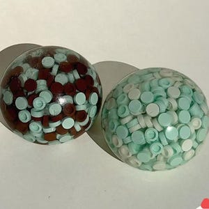 May include: A set of three ceramic mugs with a speckled, matte finish. The mugs are in shades of cream, light gray, and dark gray. Each mug has a simple, minimalist design and a rounded handle.