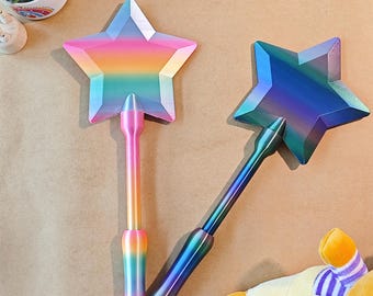 May include: Two star-shaped wands with iridescent finishes. One wand has a rainbow color scheme, while the other is primarily blue and purple. The wands have long, slender handles and are likely toys or decorative items.