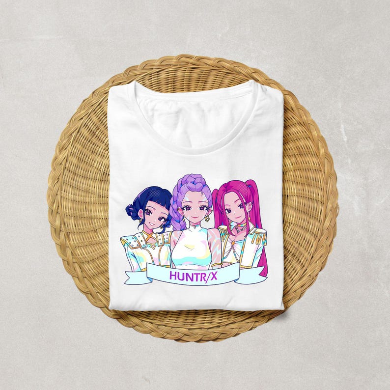 A product mockup showing a vibrant Huntrix Kpop Demon Hunters graphic applied to a physical item. The print highlights the vivid colors and crisp details of the Saja Girls anime PNG design, demonstrating its perfect application for sublimation and DTG printing.