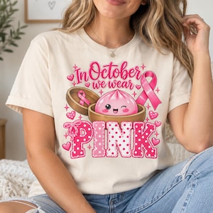 In October We Wear Pink breast cancer awareness PNG featuring a cute pink dumpling in a bamboo steamer, pink ribbon, hearts, bows, sparkles, and polka-dot lettering.