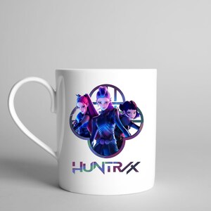 A product mockup showing a vibrant Huntrix Kpop Demon Hunters graphic applied to a physical item. The print highlights the vivid colors and crisp details of the Saja Girls anime PNG design, demonstrating its perfect application for sublimation and DTG printing.