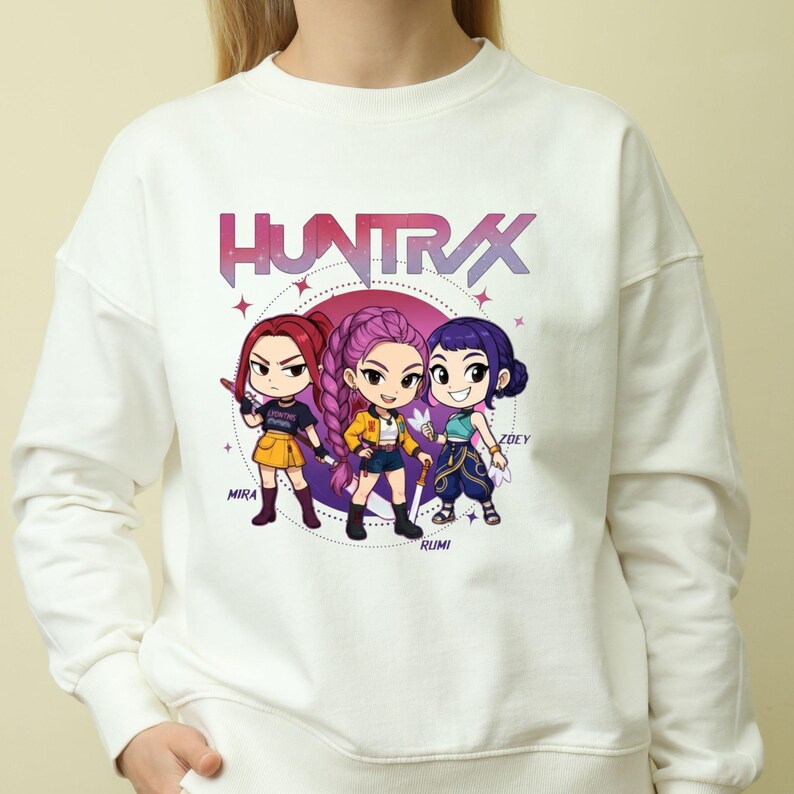 A product mockup showing a vibrant Huntrix Kpop Demon Hunters graphic applied to a physical item. The print highlights the vivid colors and crisp details of the Saja Girls anime PNG design, demonstrating its perfect application for sublimation and DTG printing.
