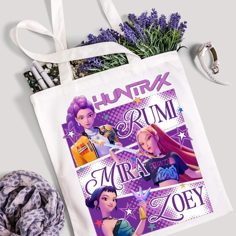 A product mockup showing a vibrant Huntrix Kpop Demon Hunters graphic applied to a physical item. The print highlights the vivid colors and crisp details of the Saja Girls anime PNG design, demonstrating its perfect application for sublimation and DTG printing.