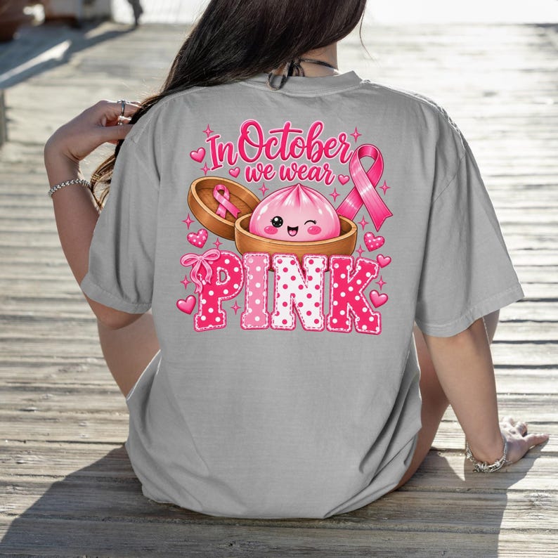 In October We Wear Pink breast cancer awareness PNG featuring a cute pink dumpling in a bamboo steamer, pink ribbon, hearts, bows, sparkles, and polka-dot lettering.
