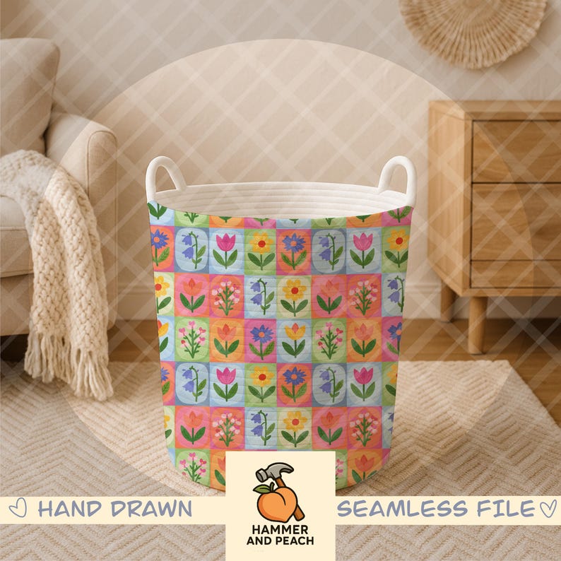 Op de afbeelding: Een cilindrische wasmand met een kleurrijk bloemenpatroon. Het ontwerp heeft een raster van vierkanten, elk met een andere bloemenillustratie. De mand heeft witte touwhandvatten en de tekst "HAND DRAWN" en "SEAMLESS FILE".
