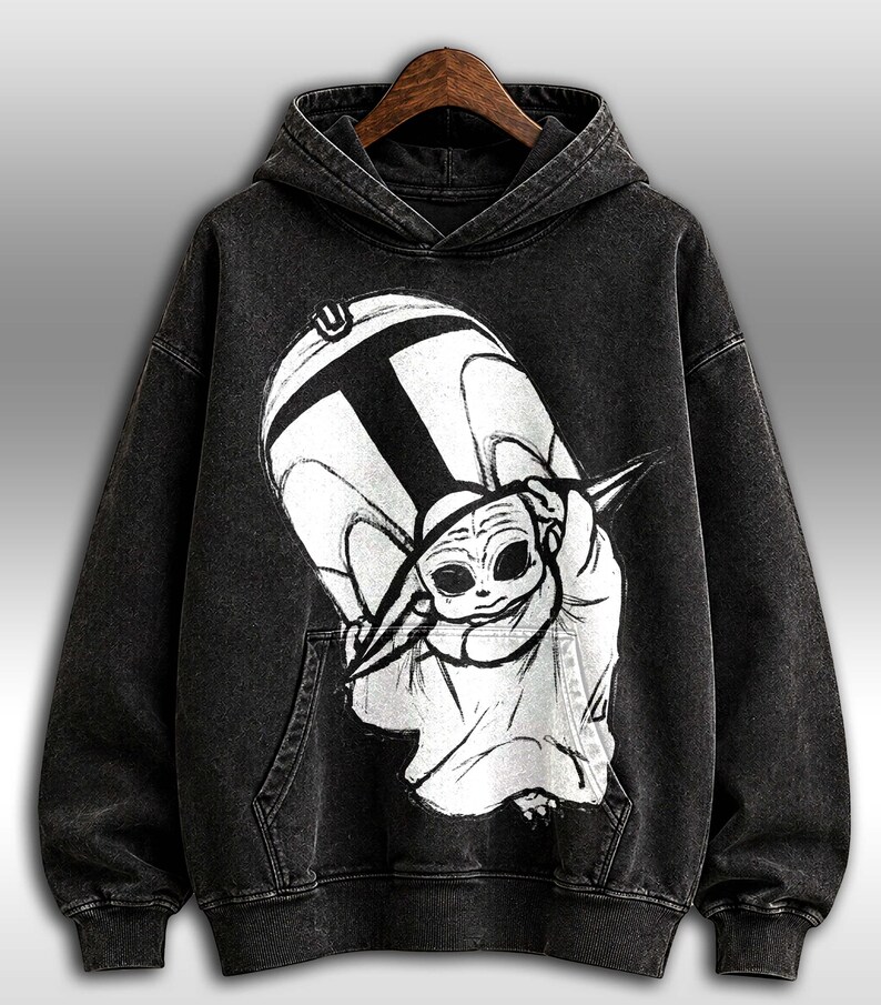 Peut inclure: Sweat-shirt &agrave; capuche noir avec un grand motif en noir et blanc d'un personnage de dessin anim&eacute;. Le sweat-shirt a une poche kangourou et une capuche &agrave; cordon. Le motif repr&eacute;sente un personnage avec de grands yeux et une t&ecirc;te pointue.