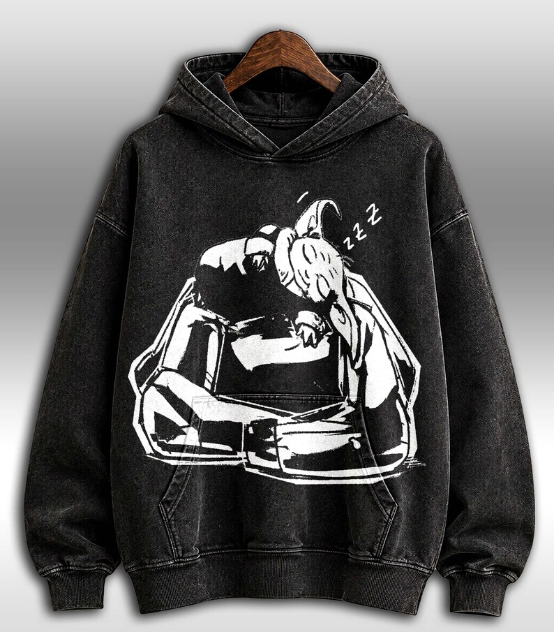 K&ouml;nnte beinhalten: Schwarzer Kapuzenpullover mit einer wei&szlig;en Grafik einer schlafenden Person, mit dem Wort "zzz" &uuml;ber dem Kopf. Der Pullover hat eine Vordertasche und eine Kapuze mit Kordelzug. Der Stoff hat einen verwaschenen Vintage-Look.