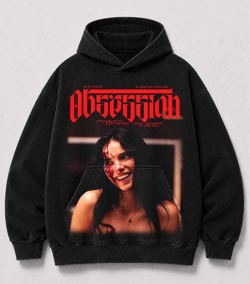 May include: A black hooded sweatshirt featuring a large red graphic print on the chest. The text reads "OBSESSION" in a bold, stylized font above a photographic image of a smiling person with red markings on their face and neck area.
