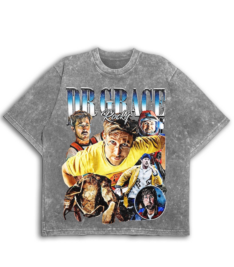 May include: Grey acid wash t-shirt with a collage of images and the text "DR GRACE Rocky" in blue and white. The design includes a central portrait of a man in a yellow shirt, surrounded by other portraits.
