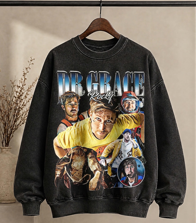 May include: Black vintage-style sweatshirt with a graphic of a person and the text "DR GRACE Rocky" in blue and white. The graphic includes multiple images of the person. The sweatshirt has a crew neck and long sleeves. The garment has a faded appearance.