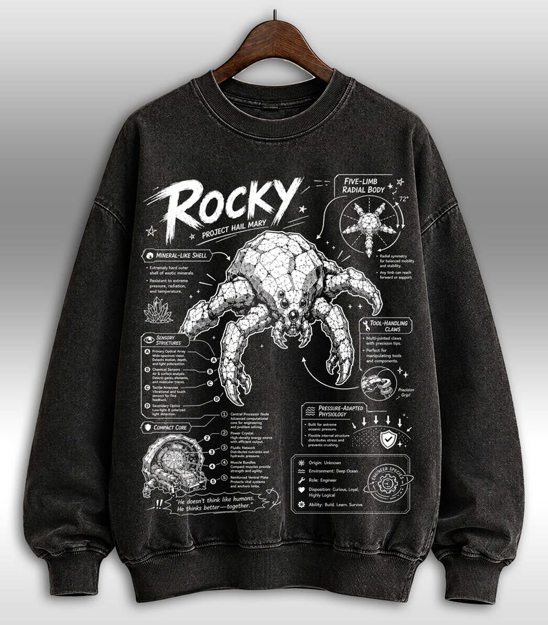 May include: Dark grey crew neck sweatshirt featuring a detailed crab-like creature illustration with scientific diagrams. The word "Rocky" is above the creature. Text includes "Project Hail Mary".
