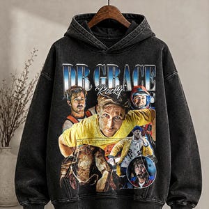 May include: Black hooded sweatshirt with a distressed graphic featuring the text "DR GRACE Rocky" and multiple images of a person. The sweatshirt has long sleeves and a drawstring hood.