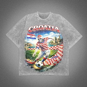 May include: Gray t-shirt featuring a graphic of a skeleton soccer player in a Croatian uniform kicking a soccer ball. The word "CROATIA" is arched across the top. The design includes a Croatian flag and a castle.