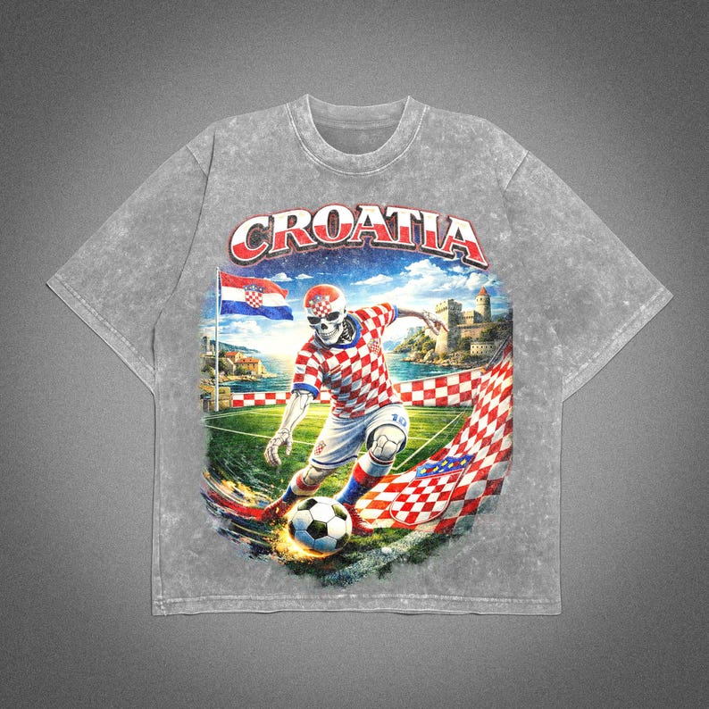May include: Gray t-shirt featuring a graphic of a skeleton soccer player in a Croatian uniform kicking a soccer ball. The word "CROATIA" is arched across the top. The design includes a Croatian flag and a castle.