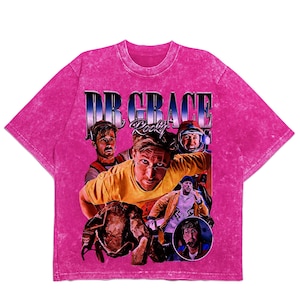 May include: A pink acid wash t-shirt with a graphic featuring the text "DR GRACE Rocky" and a collage of images. The images show a person in different outfits. The t-shirt has a crew neck and short sleeves.