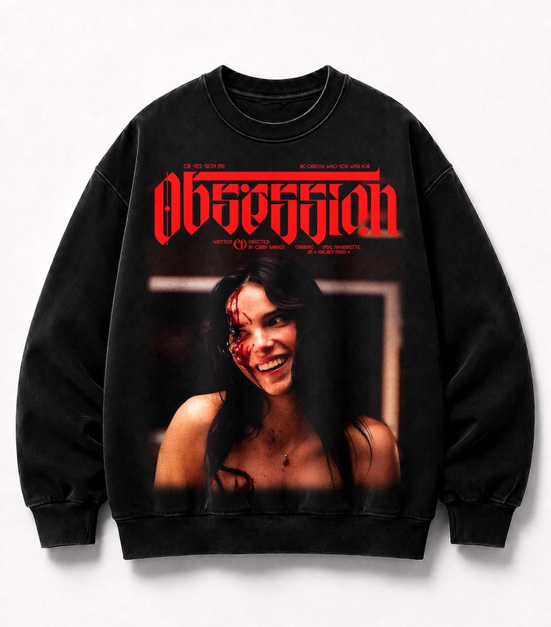 May include: A black crewneck sweatshirt featuring a graphic print of a smiling person with blood on their face. The word "OBSESSION" is printed in large red letters above the image, with additional small text details included in the design.