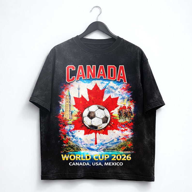 May include: Black t-shirt featuring a soccer ball on a red maple leaf, with the word "CANADA" in red and white. The shirt also displays "WORLD CUP 2026" and the host countries: Canada, USA, and Mexico.
