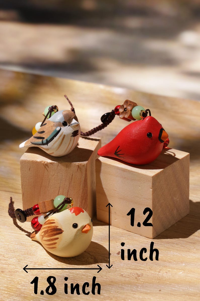 May include: Three small bird-shaped charms with brown, red, and cream painted details, each featuring a dark cord and decorative beads. The charms are displayed on wooden blocks with text indicating a height of 1.2 inches and width of 1.8 inches.