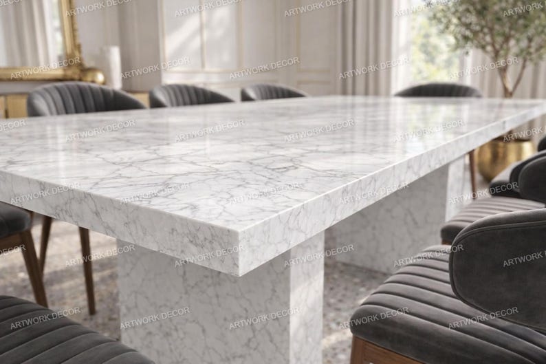 May include: A rectangular dining table featuring a white marble top with grey veining and a matching thick marble pedestal base. The table is surrounded by several dark grey upholstered chairs with vertical channel tufting on the backrests.