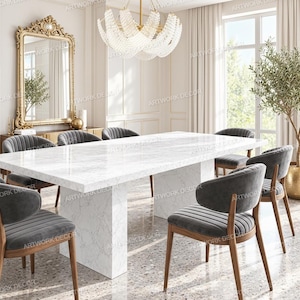 May include: A rectangular white marble dining table with a thick pedestal base, surrounded by six dark gray upholstered chairs with wooden legs. The chairs feature vertical channel tufting on the backrests and curved, rounded armrests.