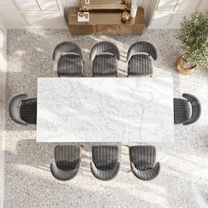 May include: A rectangular dining table with a white marble top featuring grey veining, surrounded by eight dark grey upholstered chairs with curved backrests, arranged in a symmetrical layout within a room with light-colored walls and flooring.