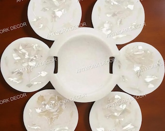 May include: A white marble ashtray and six matching coasters. Each coaster and the ashtray feature a rose design inlaid with mother-of-pearl. The text "ARTWORK DECOR" is printed on the coasters.
