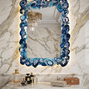 May include: A rectangular wall mirror featuring a frame composed of numerous polished blue agate slices. The edges of the frame are illuminated by integrated backlighting, creating a glowing effect around the perimeter of the blue stone border.