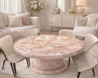 May include: A round, pink quartz coffee table with a pedestal base, surrounded by four cream-colored chairs with black legs. The table is the focal point of a living room setting, with a sofa, chairs, and decorative elements in the background.
