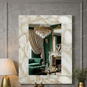 May include: A rectangular wall mirror featuring a wide frame constructed from polished, translucent white and beige agate stone slices. The mirror surface reflects a room with a crystal chandelier, green furniture, and a fireplace mantel.