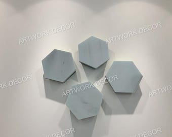 Könnte beinhalten: Vier sechseckige Wanddekorationen mit hellgrauem Marmormuster sind an einer weißen Wand angeordnet. Der Text "ARTWORK DECOR" ist auf die Wand gedruckt. Die Teile werfen Schatten.