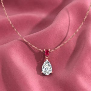Zierlicher Moissanite Rubin Teardrop Anhänger mit einem lebhaften Pear Cut Center Stone, der von einer zarten Halo-Natur-inspirierten Birthstone-Halskette umrahmt wird