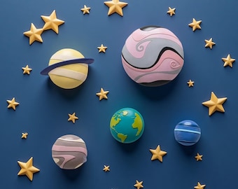 May include: A collection of colorful planet-shaped decorations and golden star accents against a deep blue background. The planets feature various designs and colors, including yellow, pink, and blue, creating a whimsical space theme.
