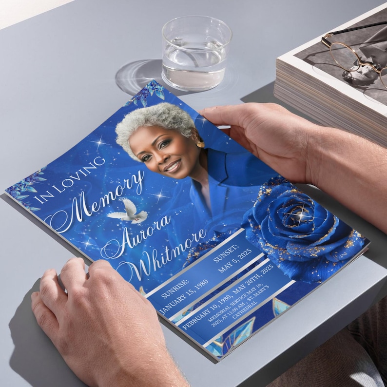 May include: A memorial program with a blue and white design. The cover features a portrait of a woman, a blue rose, and the text "In Loving Memory Aurora Whitmore". The program includes dates and memorial service details.