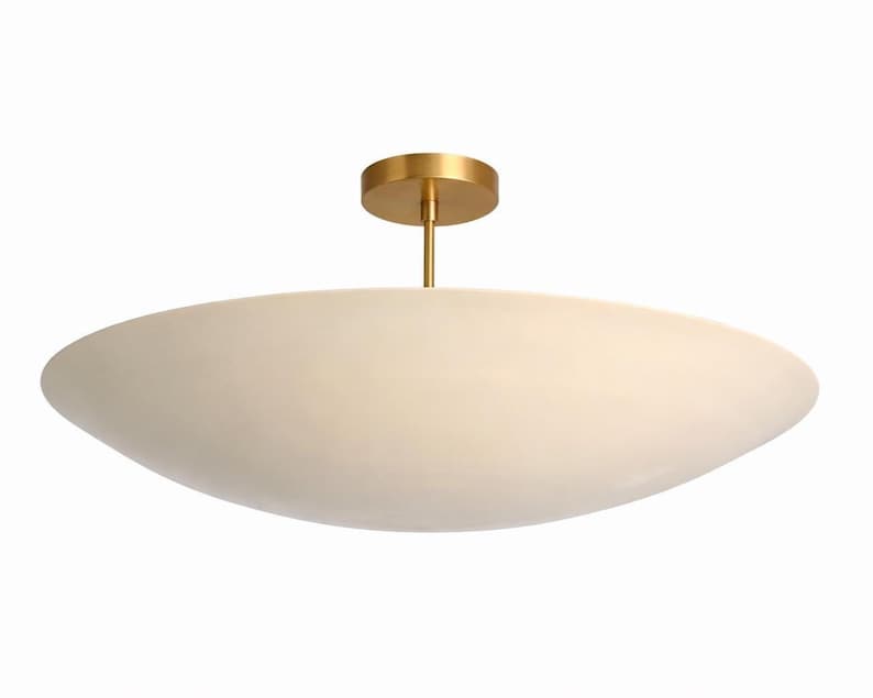 K&ouml;nnte beinhalten: Eine moderne Deckenleuchte mit einem cremefarbenen, ovalen Schirm. Die Leuchte wird von einer goldfarbenen, kreisf&ouml;rmigen Basis und einer schlanken Stange abgeh&auml;ngt. Das Design ist minimalistisch und elegant, passend f&uuml;r verschiedene Einrichtungsstile. Ca. 60 cm lang.