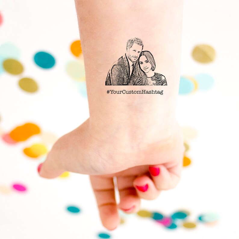 Op de afbeelding: Een tijdelijke tattoo met een zwart-witte lijntekening van een stel. Het stel omarmt elkaar en de vrouw draagt een jurk. De tattoo bevat de tekst "#YourCustomHashtag".