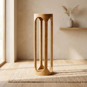 Puede incluir: Un soporte para plantas de madera marrón claro con una parte superior e inferior circulares. El soporte presenta cuatro soportes verticales arqueados. El soporte está colocado sobre una alfombra tejida en una habitación con una paleta de colores neutros.