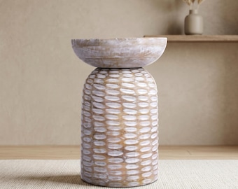 Puede incluir: Una mesa auxiliar decorativa de madera con un diseño único. La mesa presenta una base texturizada de color marrón claro con un patrón blanco y una parte superior en forma de cuenco. La mesa mide aproximadamente 61 cm de altura.