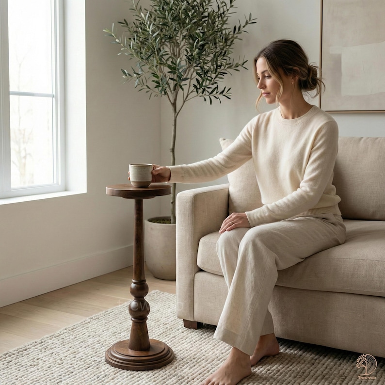 May include: A dark brown, wooden side table with a round top and a decorative, turned column. The table is holding a ceramic mug. The table is approximately 28 inches tall.