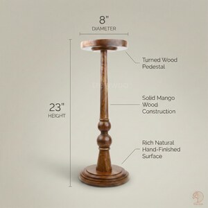 May include: A turned wood pedestal with a rich, hand-finished surface. The solid mango wood construction has a diameter of 8 inches and a height of 23 inches.