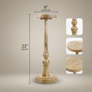 May include: A wooden pedestal stand with a round top, 8 inches in diameter, and a height of 23 inches. The stand has a decorative base and a central column with a series of rounded accents. The wood has a natural, light brown finish.