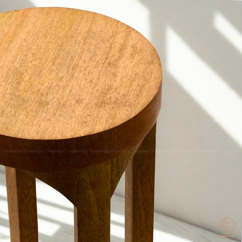 Op de afbeelding: Houten kruk met een ronde zitting en drie poten. De kruk is gemaakt van lichtbruin hout en heeft een natuurlijk houtnerfpatroon. Het ontwerp is eenvoudig en modern, geschikt voor diverse interieurstijlen. Hoogte ongeveer 45 cm.