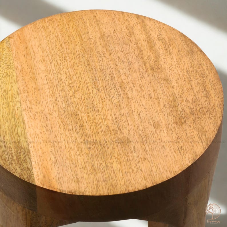 Op de afbeelding: Een ronde houten kruk met een lichtbruine afwerking. De kruk heeft een cirkelvormige zitting en een cilindrische basis. De houtnerf is zichtbaar op het oppervlak. De kruk is een eenvoudig, functioneel meubelstuk.