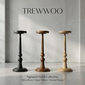 May include: Three decorative pedestals in matte black, classic walnut, and natural mango finishes. Each pedestal has a round base, a central column with decorative elements, and a circular top. The text "TREWWOO" is at the top.