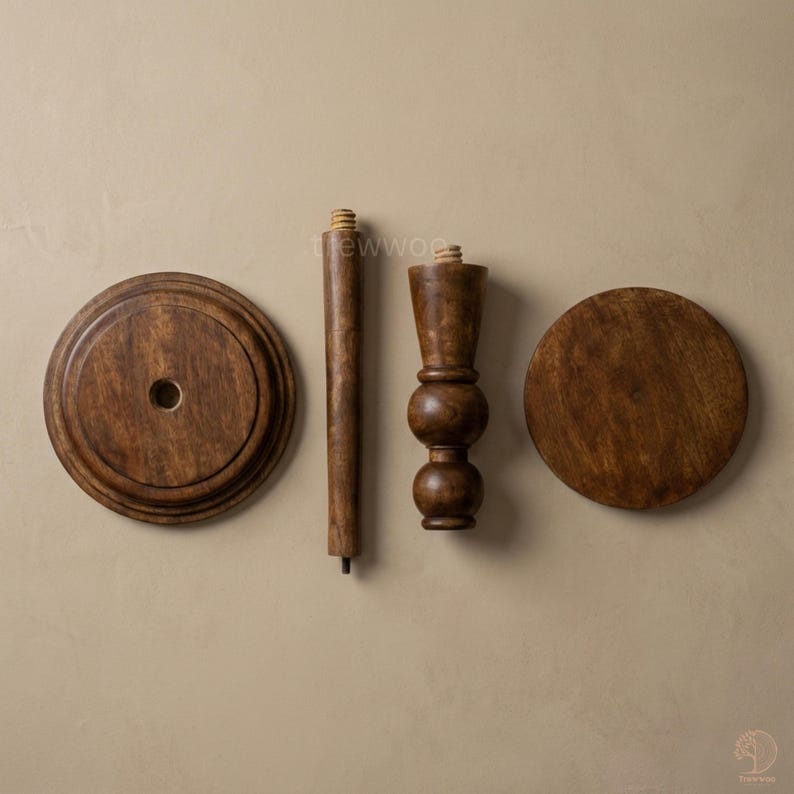 May include: Four wooden furniture components, including two circular pieces, a long, cylindrical leg, and a decorative, turned leg. The wood has a warm, brown stain. The pieces are arranged against a neutral background, suggesting a DIY furniture project.