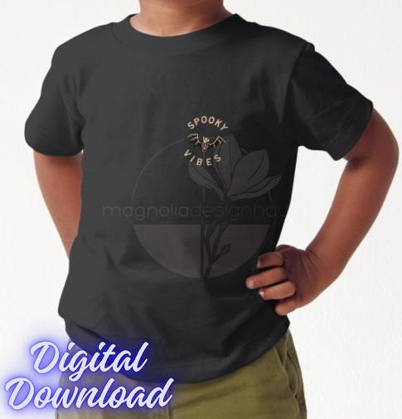 Pu&ograve; includere: T-shirt nera con grafica oro e bianca di un pipistrello, un fiore e le parole "Spooky Vibes". La maglietta presenta anche il testo "magnoliadesignhau" e "Digital Download" in carattere azzurro.