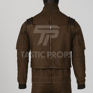 Pu&ograve; includere: Giacca marrone con collo alto e cerniera centrale. La giacca presenta cuciture geometriche sulle maniche e la scritta "TASTIC PROPS". Design unico.