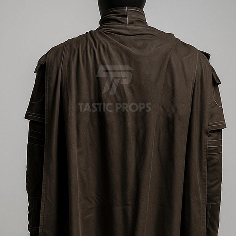May include: A brown cloak with a high collar and shoulder detailing. The back of the cloak is visible, with the text "TASTIC PROPS" printed on the fabric. The cloak has a cape-like design.