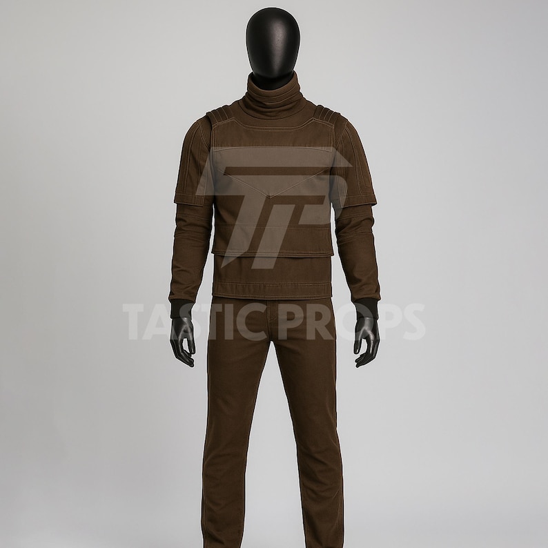 Pu&ograve; includere: Un completo tattico marrone esposto su un manichino. Il completo comprende una maglia a collo alto, un gilet e pantaloni. Il testo "TATIC PROPS" &egrave; visibile nella parte inferiore dell'immagine.