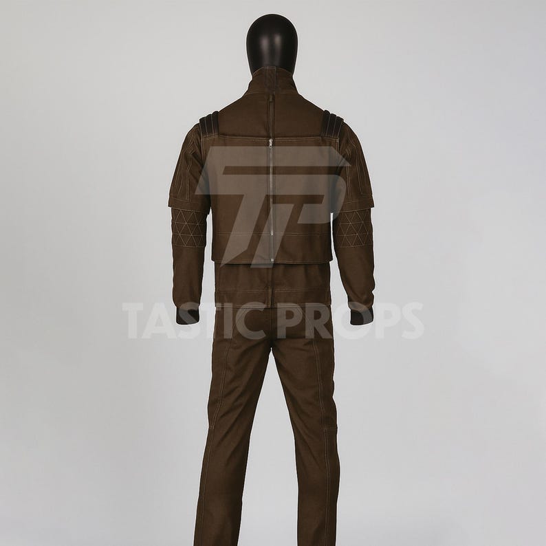 Pu&ograve; includere: Un costume marrone esposto su un manichino. L'outfit include una giacca con cerniera e spalline, e pantaloni abbinati. La giacca ha cuciture geometriche sulle maniche. Il manichino ha una testa nera.