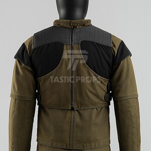 May include: Olive green jacket with black shoulder accents and a high collar. The jacket features a zipper closure and the text "TASTIC PROPS".